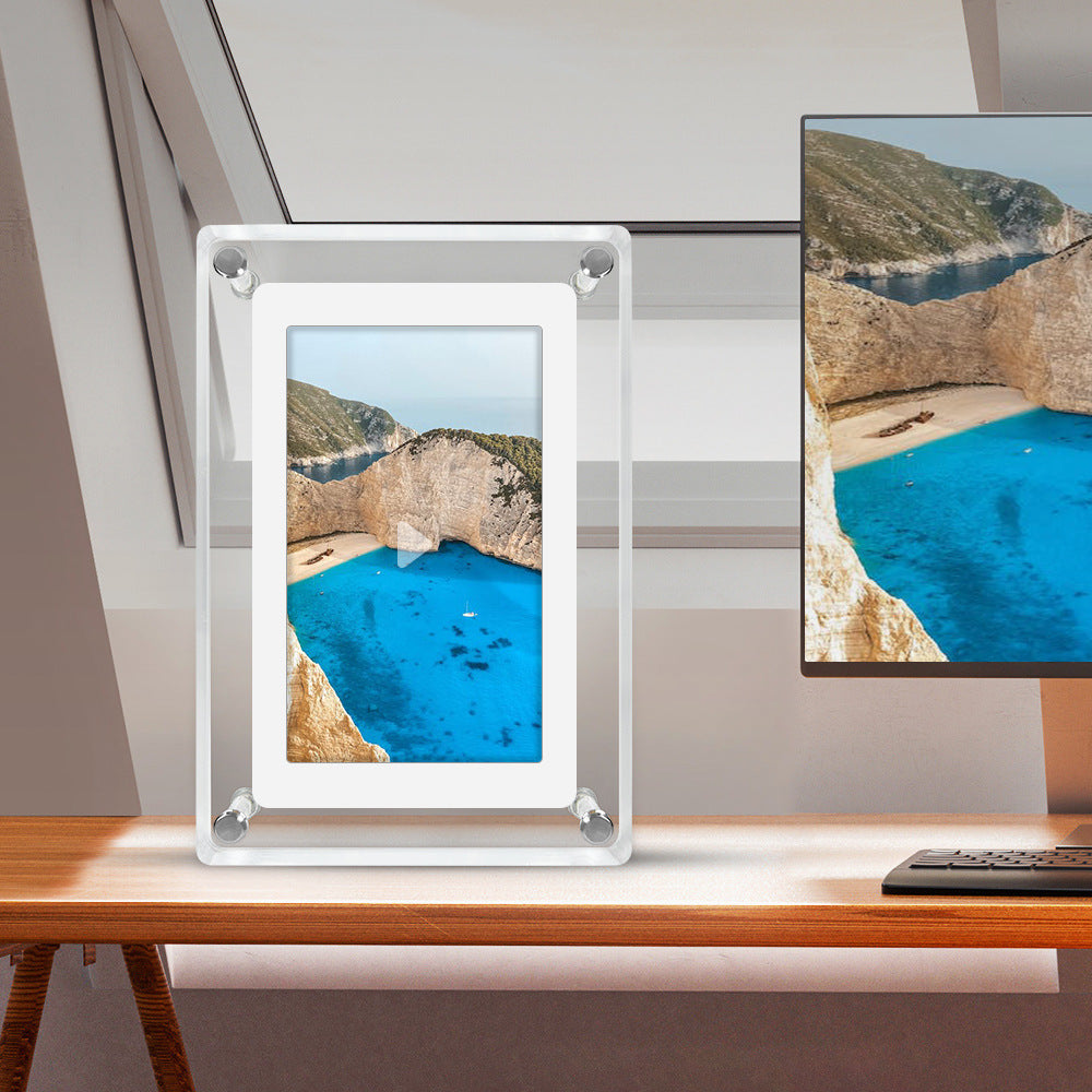 Digital photo frame displaying a scenic image of a blue lagoon with mountains, next to a television showing the same view.